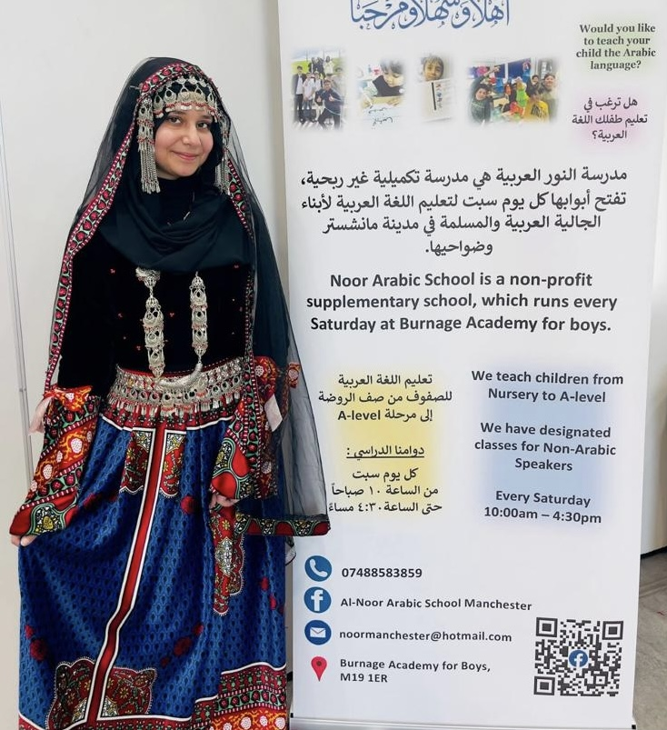 A teacher in traditional Yemeni dress at a council stall