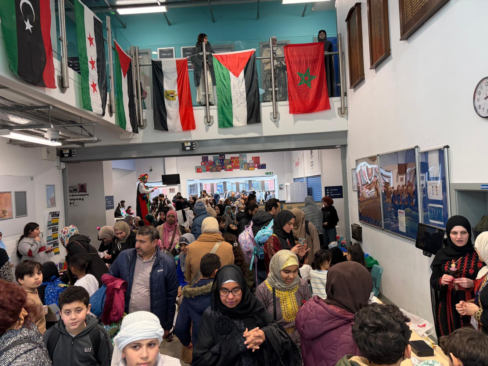 Crowds at the culture day bazaar, with a clown on stilts in Palestinian colours